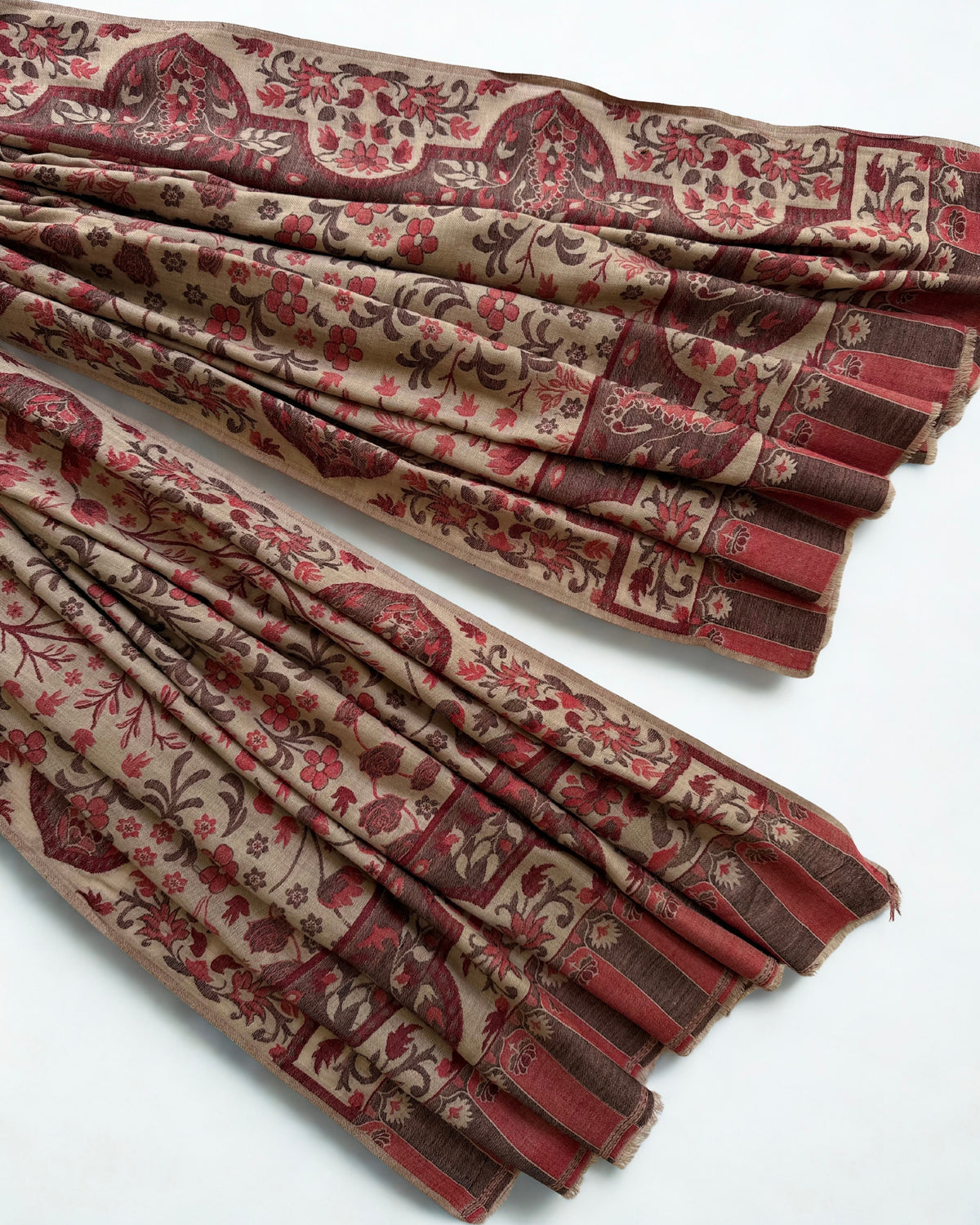 Close view of the rosewood flowering sprays and scalloped paisley border woven into a taupe pashmina ground
