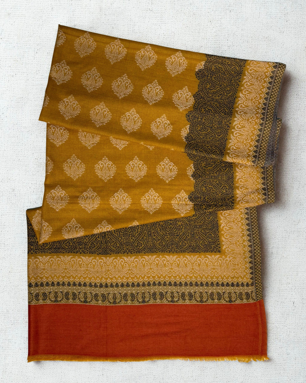 Mustard Kani border pashmina shawl folded back to show the corner of the woven paisley border and the rust end panel