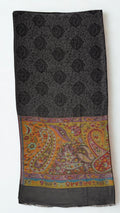 Dark charcoal pashmina ring shawl folded, showing the black paisley medallion lattice and a saffron and crimson paisley palla