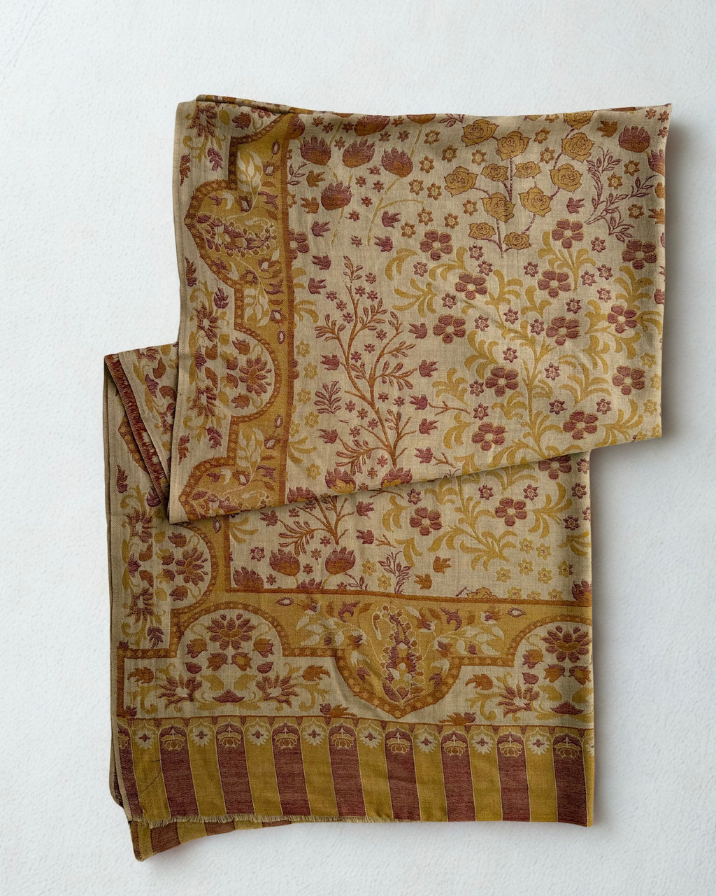 Sand and rose Kani pashmina shawl folded back to show the reverse of the woven floral pattern and the striped end band