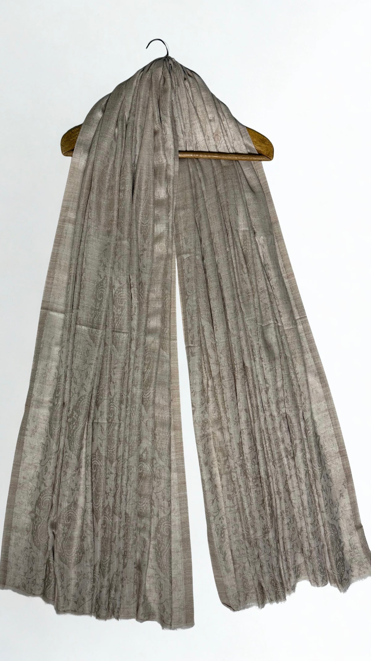 Stone taupe pashmina ring shawl hanging from a wooden hanger, showing the woven paisley and lustrous edge stripes