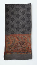 Charcoal pashmina ring shawl folded flat, showing the black paisley medallion lattice and the deep rust, copper and sage paisley pallu