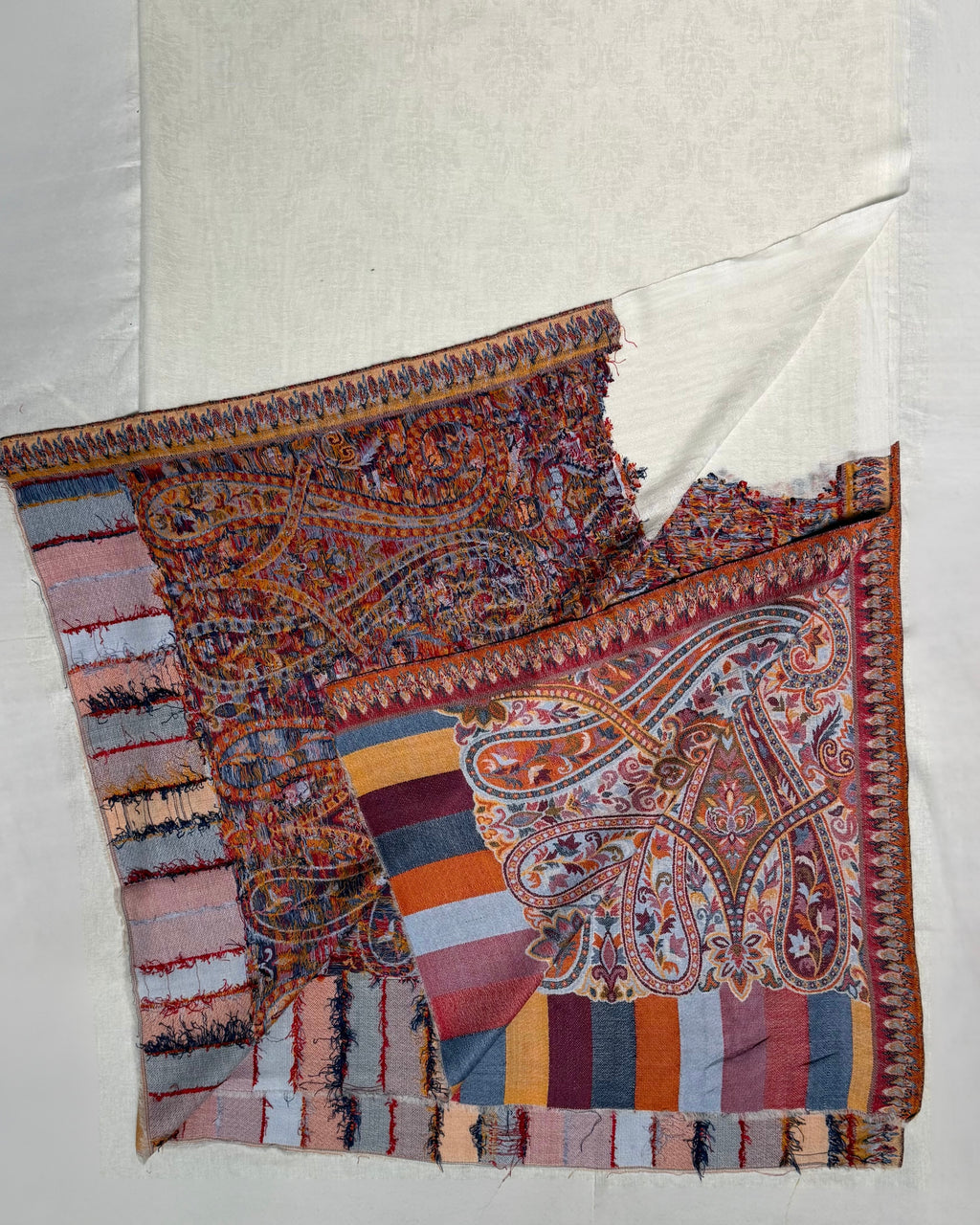 Close view of the woven paisley end panel in terracotta, blue, rose and gold on the white pashmina ground