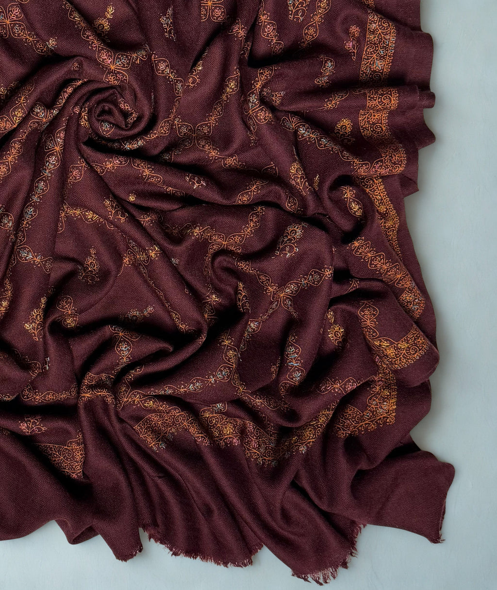 Close-up of the copper trellis and hand-embroidered buti on the wine Swati Shahtoosh shawl