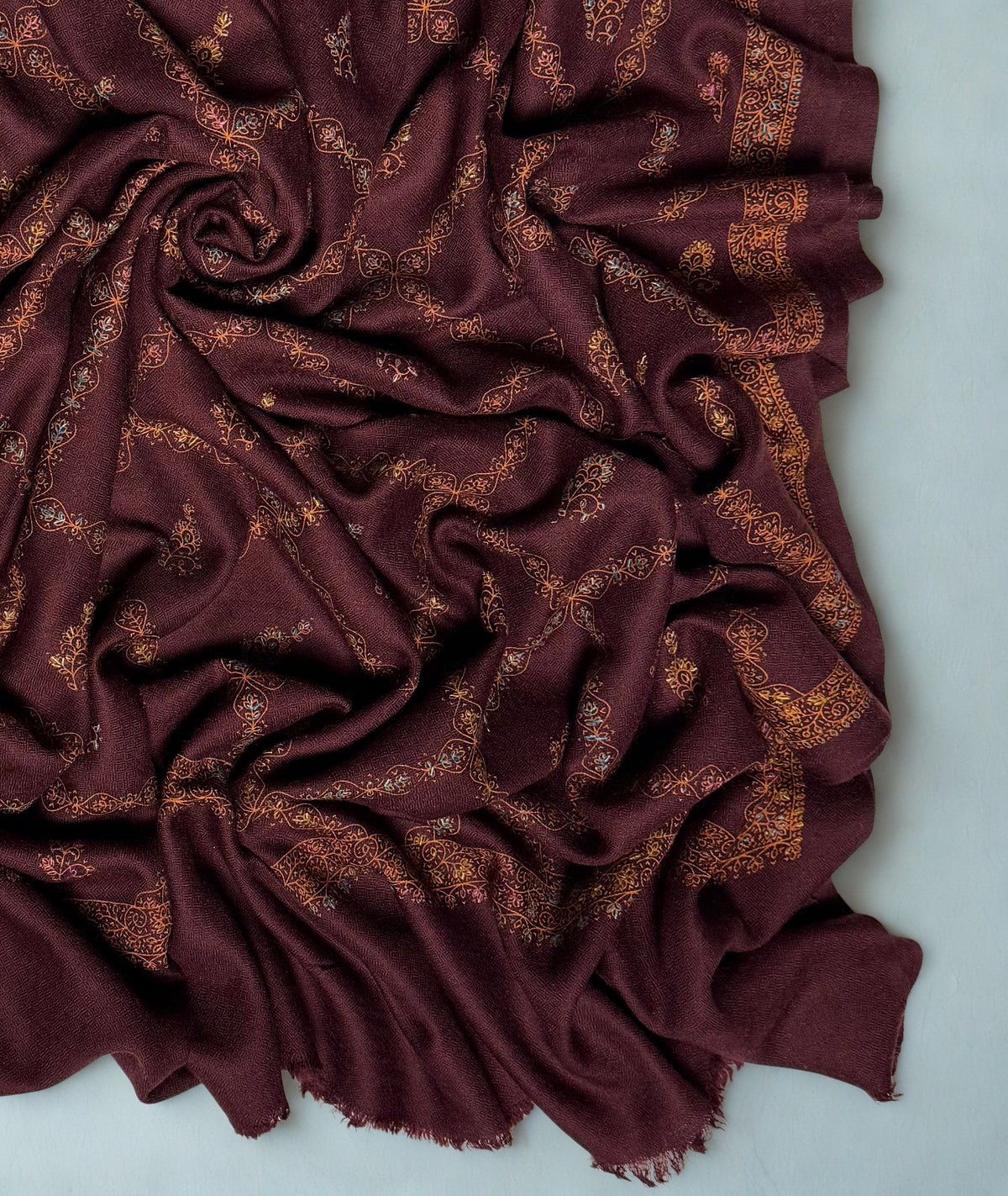 Close-up of the copper trellis and hand-embroidered buti on the wine Swati Shahtoosh shawl