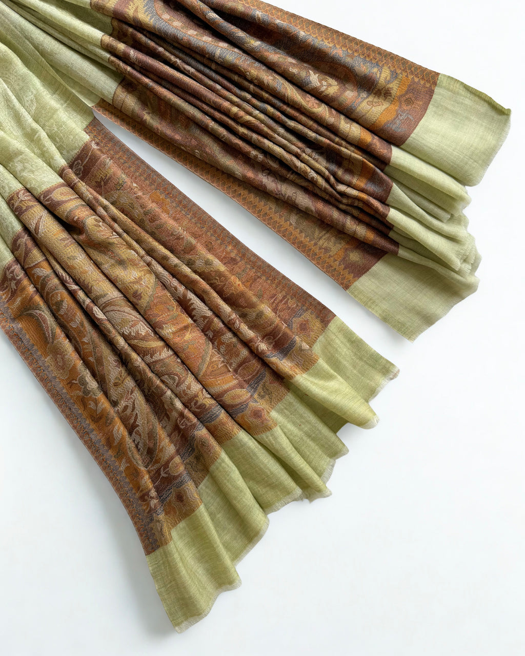 Pistachio pashmina shawl swirled to show its drape above the amber border