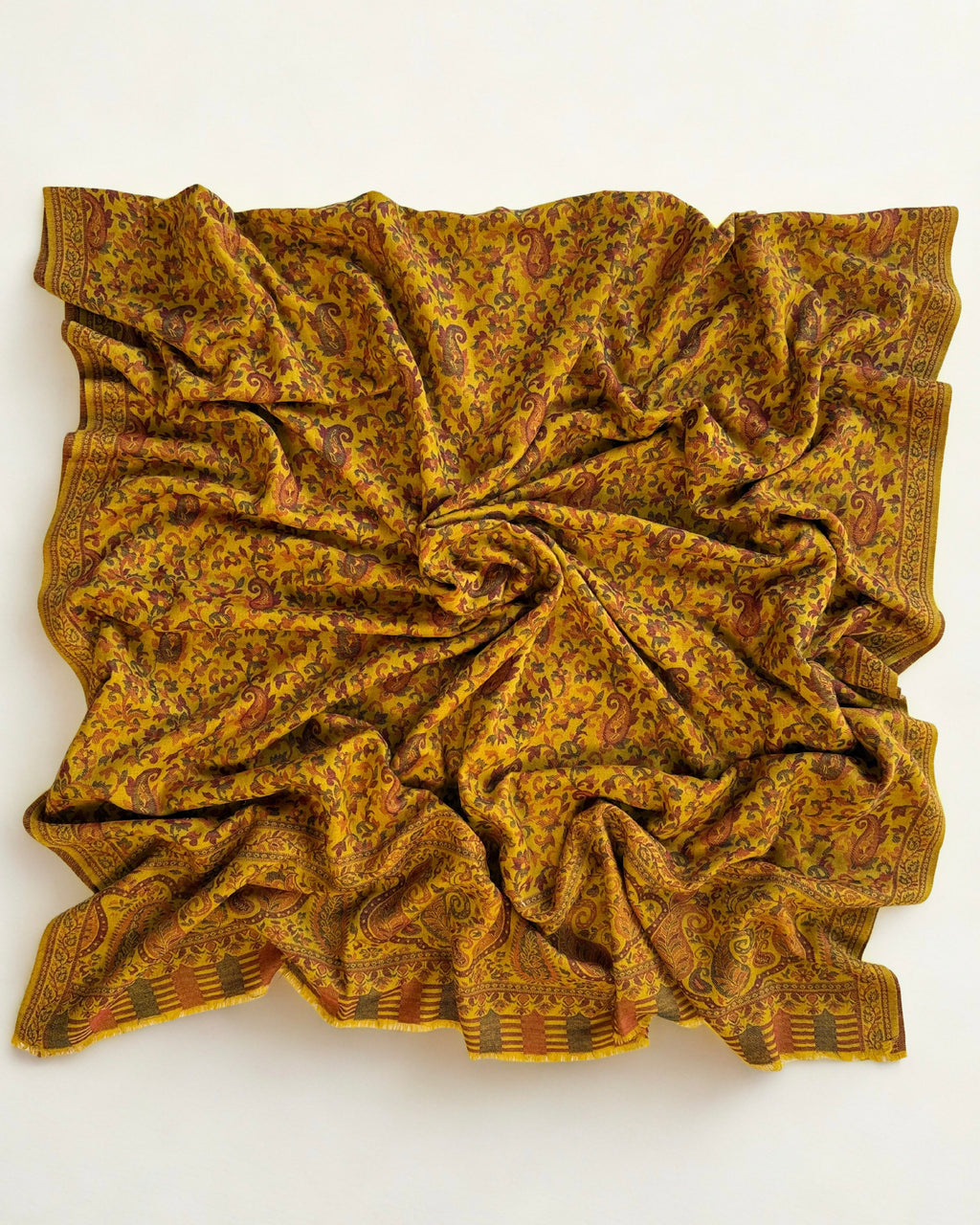 Close view of the Kani handwoven paisley motifs in rust and green on a mustard pashmina ground