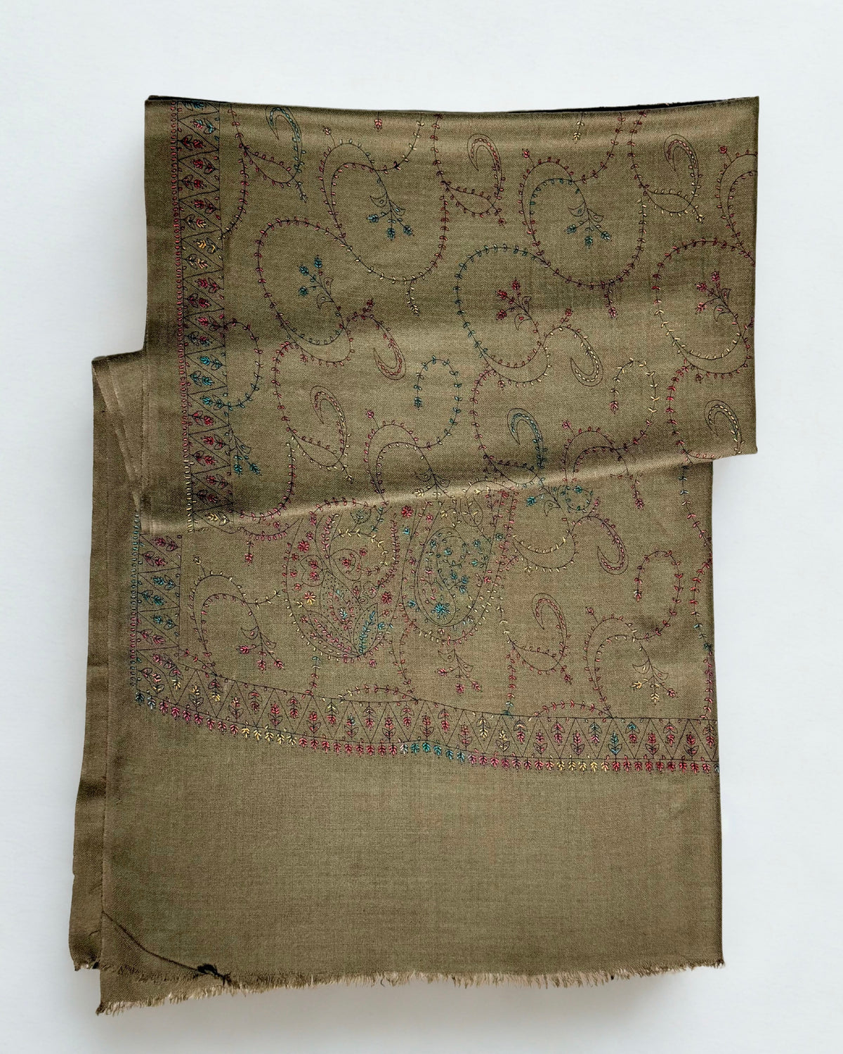 Olive brown Swati Shahtoosh shawl folded in layers, the drawn paisley jaal and toothed border running across the cloth