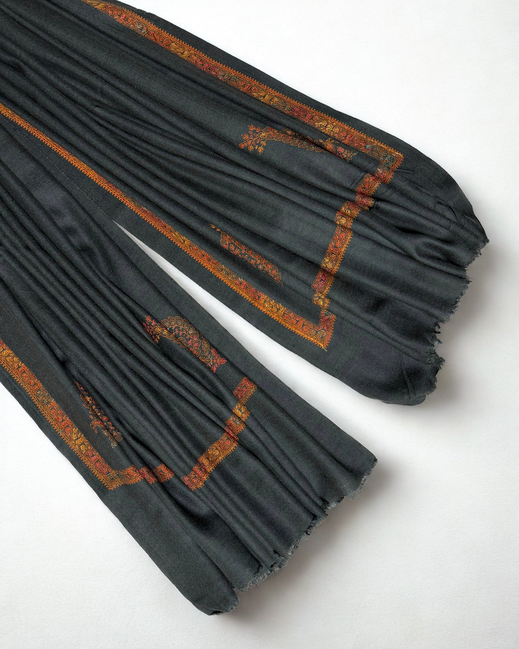 Ends of the charcoal Swati Shahtoosh shawl showing the rust border framing the plain field
