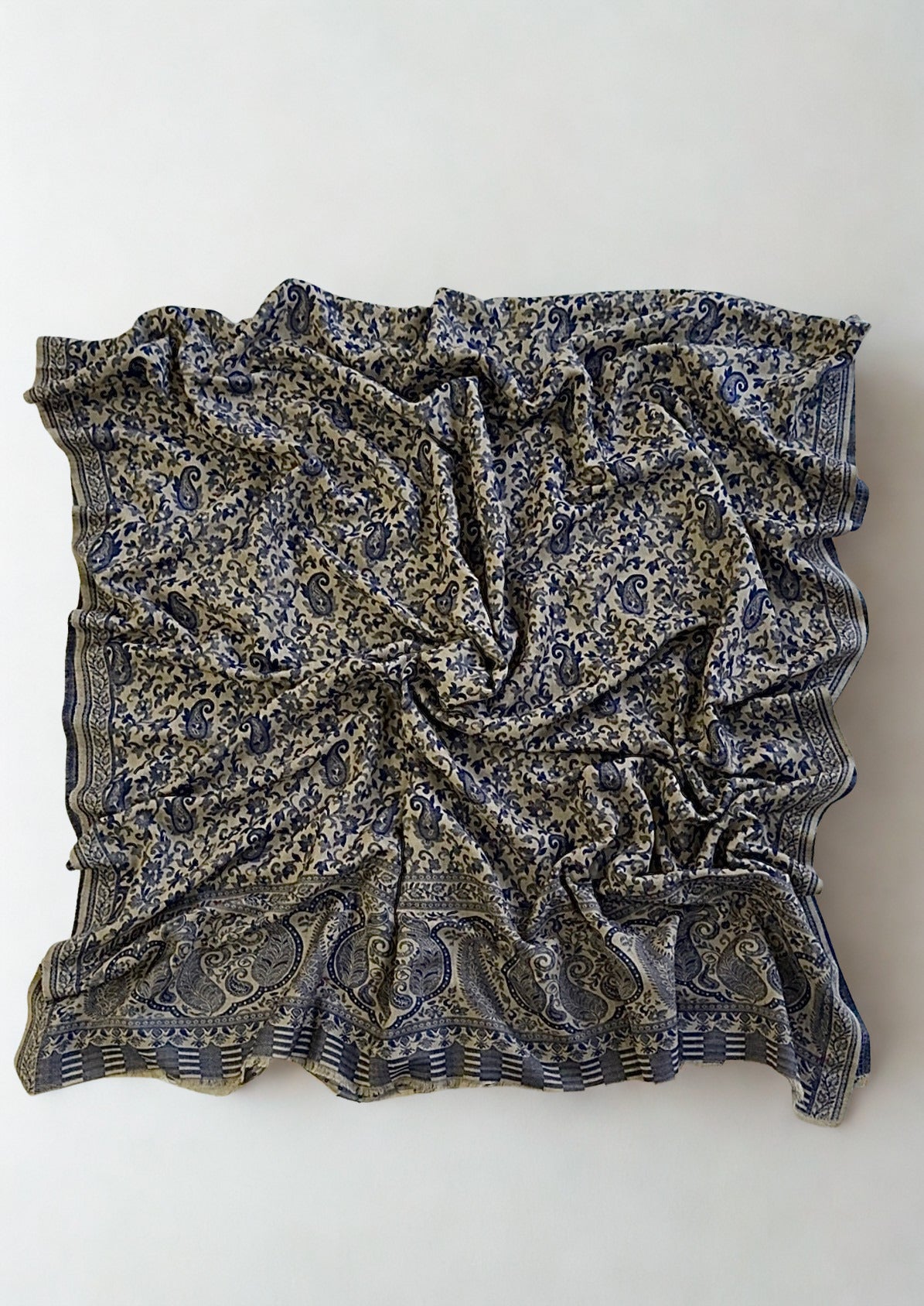 Close view of the fine navy Kani paisley weave and border detail on a stone pashmina ground