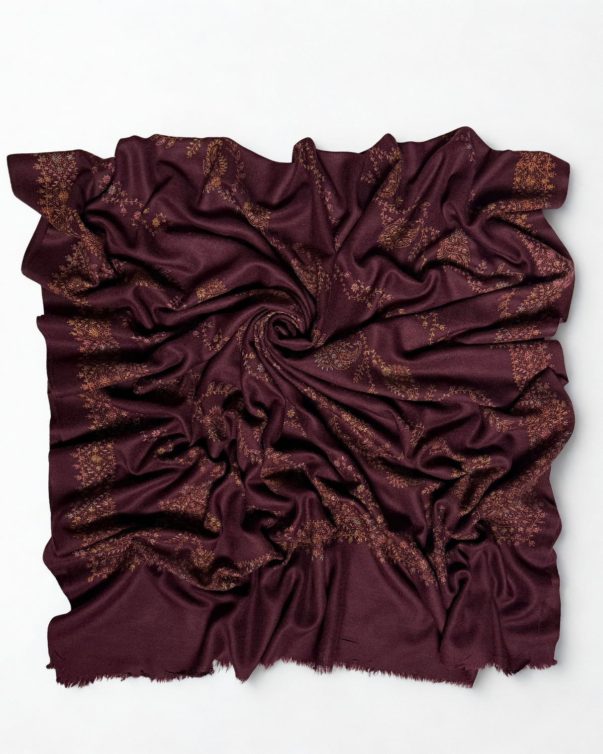 Deep maroon hand-embroidered Swati Shahtoosh shawl swirled from above, showing the embroidered border and fringed edges